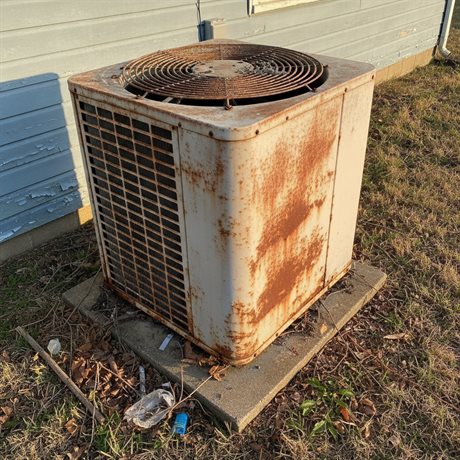 An old, rusty HVAC condenser unit that needs replacing